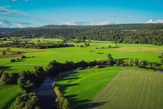 Aerial view of Unica or Unec river on Planinsko polje field in the late summer. Green fields and forests seen from above.