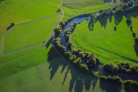 Aerial view of Unica or Unec river on Planinsko polje field in the late summer. Green fields and forests seen from above.