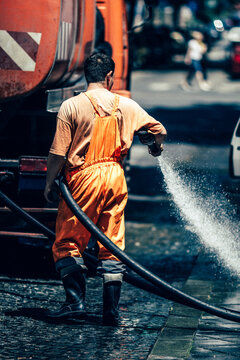 street sweeper, A street-sweeping worker using a hose to clean off litter
