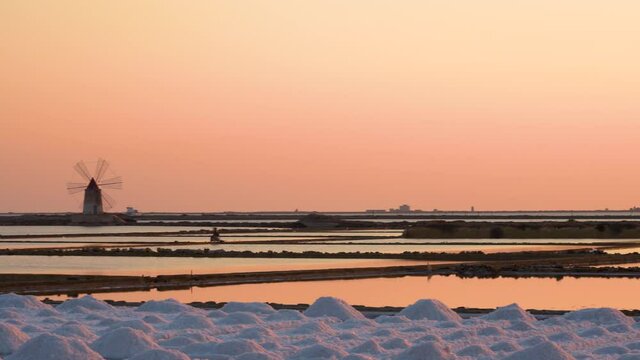 Salt ponds near Trapani in Sicily in Italy at sunset with Mozia island and wind mills.