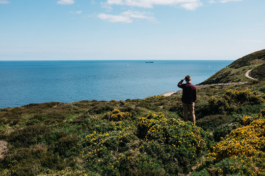 young man looking out at irish sea from shoreline