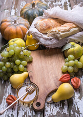 Natural organic fruits grape, pumpkins, sweet honey and fresh bread on a wooden board.