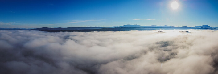 Obraz premium Early morning drone panorama of Planinsko Polje field in Slovenia during thick fog over the plain, with only higher hills such as Slivnica are seen sticking out.