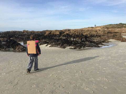 boy walking on the beach wearing a box