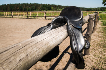 Horse saddle on a wooden rural fence.