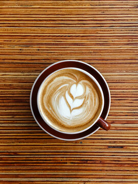 Cappuccino cup with design on striped wood table