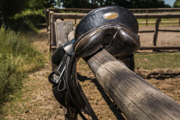Back view of leather horse saddle on a wooden fence.