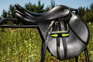 Black leather saddle for horse on a supporting fixture.