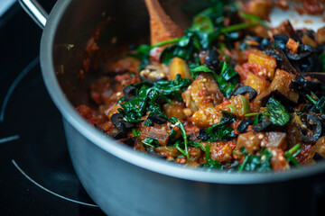 Guiso vegetariano close up berenjena espinacas hojas verdes jitomate cocido olla vegano