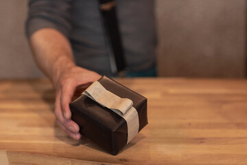 A man holding a gift box wrapped with black wrapping paper and a bow. Gentleman giving a present during festive season, Christmas or fathersday