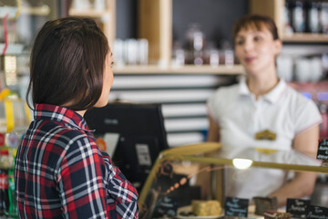 Young female customer talking with cashier in shop