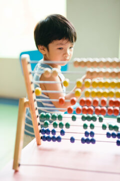 Toddler playing with a colourful abacus indoor (soft focus)