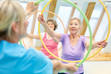 Seniors doing fitness training with hoops - obrazy, fototapety, plakaty