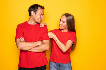 Cheerful young couple giving fists bump posing isolated on yellow background. People lifestyle concept.