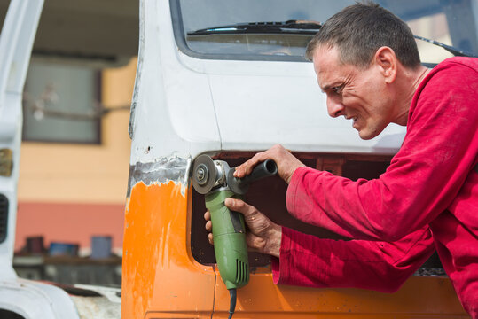 Male worker polishing metal weld with a grinder