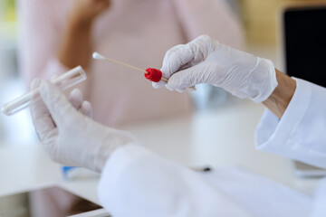Close-up of a doctor using cotton swab for PCR test at clinic.