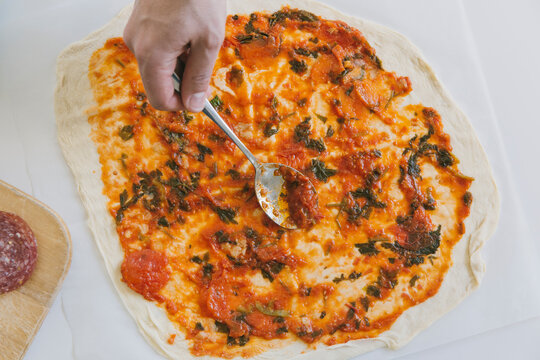 Man_&Ocirc;&oslash;&Omega;&Ocirc;&oslash;&Omega;s hand putting tomato sause on pizza base