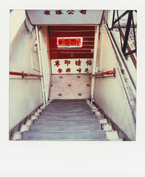 Neon OPEN sign at bottom of stairs in Chinatown restaurant (Polaroid SX-70 print)