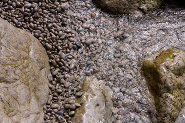 Sea stones in the sea water. Pebbles under water. The view from the top. Nautical background. Clean sea water. Transparent sea.