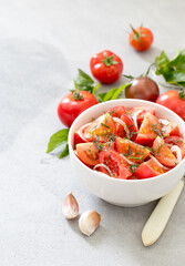 Vegetable salad of fresh tomatoes with onions and dill in a bowl on a light background
