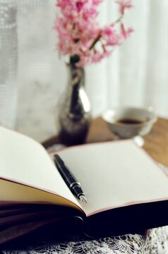 Cup of coffee and open notebook with pen on wooden desk