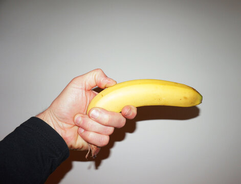 Hand holding a banana as if it was a gun