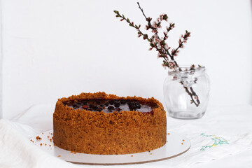 Homemade cheesecake drenched in currant jam and sprinkled with crumbs on a table covered with a white tablecloth. Selective focus.