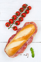 Sub sandwich baguette with salami portrait format from above on wooden board