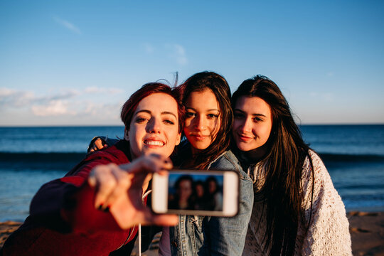 Smiling girls friends making a selfie on the beach