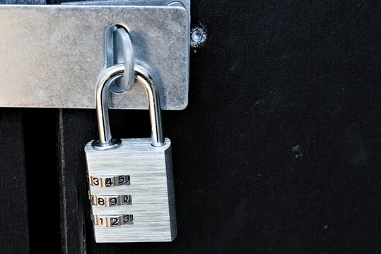 A modern padlock with numerical dials locking a black door. Close-up