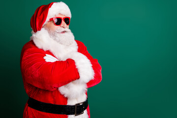 Photo of pensioner grandpa grey beard folded hands confident look empty space smiling wear red santa costume coat gloves belt sunglass headwear isolated green color background