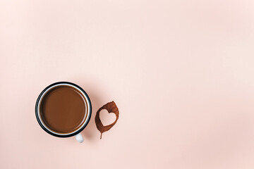 Autumn flat lay of dry leaf with heart carved and hot coffee cup on pastel beige studio background with copy space for advertisement. Thanksgiving, fall concept. Creative minimal composition