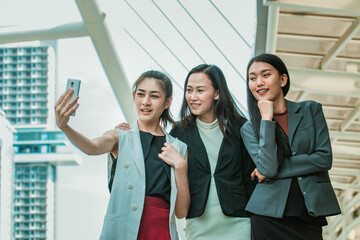 Obraz premium Businesswoman friends selfie with smartphone and pointing at screen surprised