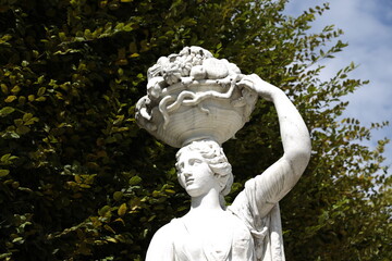 Antike Statue von einer Frau mit einer Obstschale auf dem Kopf