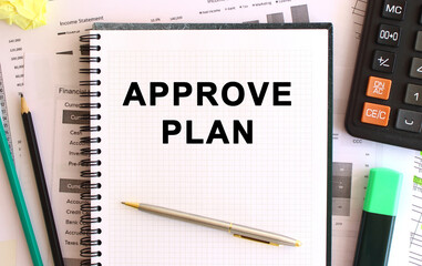 Notepad with text APPROVE PLAN on a white background, near calculator and office supplies. Business concept.