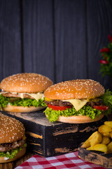 juicy burgers with a red napkin and fries on a black wooden background