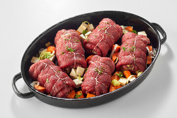 Oven dish with raw beef roulades and vegetables