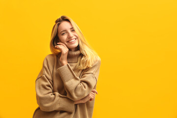 Beautiful young woman wearing knitted sweater on yellow background. Space for text
