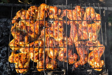 Tasty chicken wings grilling on summer barbecue. Delicious pieces of chicken meat. Close up stock photo.