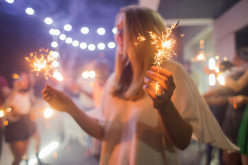 Beautiful blonde woman holding sparklers at the party