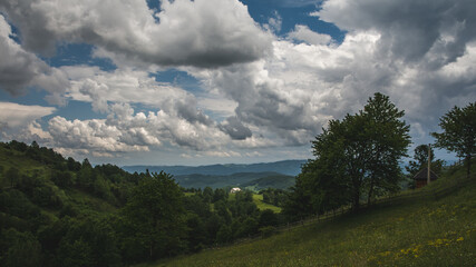 Small white house in a mountain landscape under the cloudy sky in western Serbia