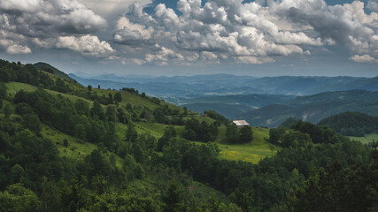 Small white house in a mountain landscape under the cloudy sky in western Serbia
