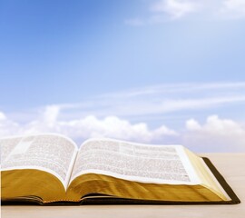 Holy Bible book on a wooden desk and sky background