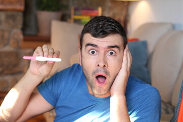 Shocked man holding pregnancy test 