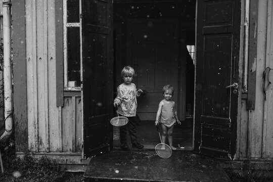 Boy and girl on rainy door step with badminton rackets