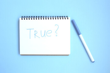 Open white notebook on a spiral on a bright blue background. Notepad with caption: true. Stationery on a blue background with space for text. Minimalism. Flat lay