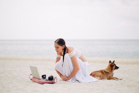 Beautiful belly dancer in white costume on the beach with a dog