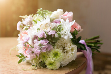 Wedding rings lie on the petals of a flower bridal bouquet.