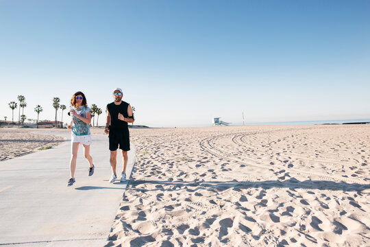 Man and woman enjoying their habitual morning run on the beach