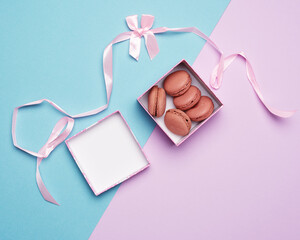 baked round multicolored macarons in square boxes on a colored pastel background